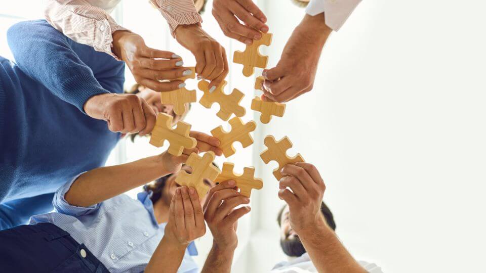 Persone con mani in primo piano che tengono pezzi di puzzle